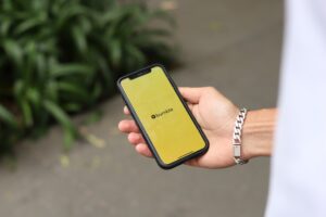 A hand holding a mobile phone with the dating application Bumble open on the screen.